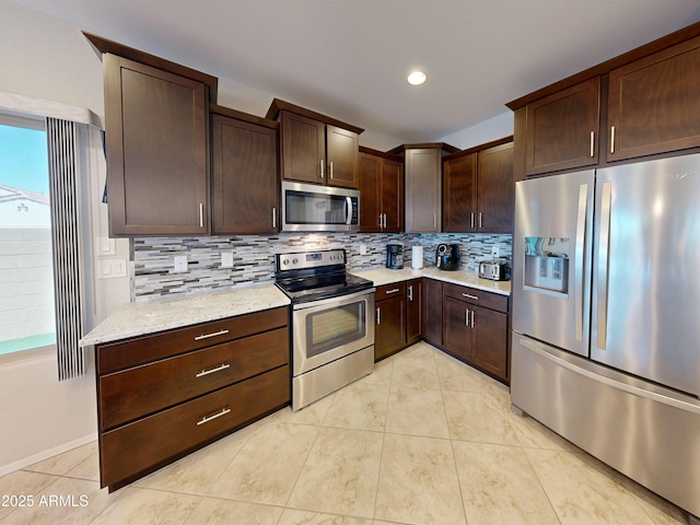 17547 W Gambit Trl, Surprise, AZ 85387 - kitchen featuring appliances with stainless steel finishes, dark brown cabinets, decorative backsplash, light tile patterned floors, and light stone counters