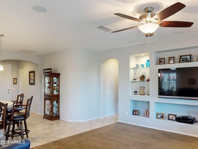 17547 W Gambit Trl, Surprise, AZ 85387 - tiled living area with arched walkways, built in shelves, a ceiling fan, carpet flooring, and baseboards