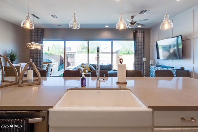 kitchen featuring dishwashing machine, visible vents, open floor plan, and a sink