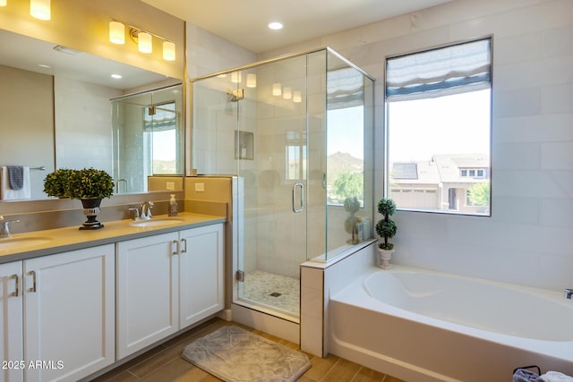 bathroom featuring a stall shower, double vanity, a sink, and a bath