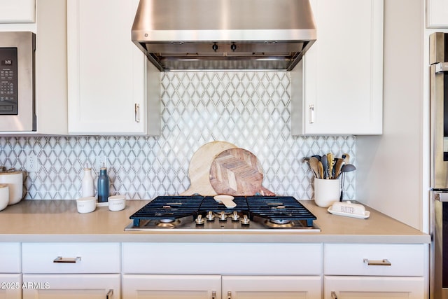 kitchen with white cabinets, light countertops, stainless steel gas stovetop, and wall chimney range hood