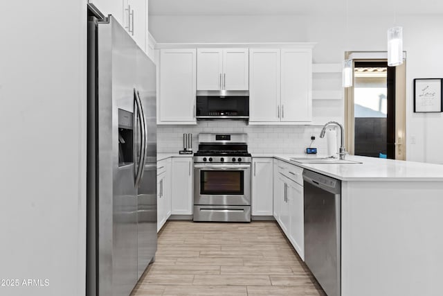 kitchen featuring appliances with stainless steel finishes, pendant lighting, white cabinetry, sink, and backsplash