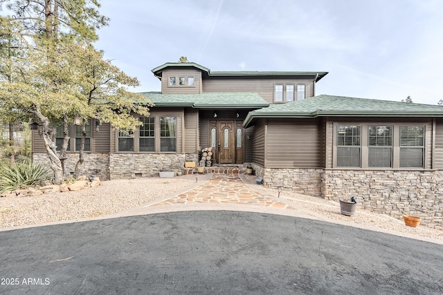 prairie-style home featuring stone siding and roof with shingles