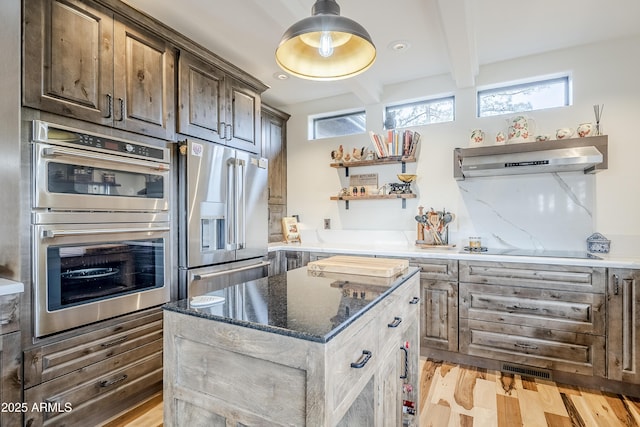 kitchen featuring open shelves, appliances with stainless steel finishes, a kitchen island, beamed ceiling, and under cabinet range hood