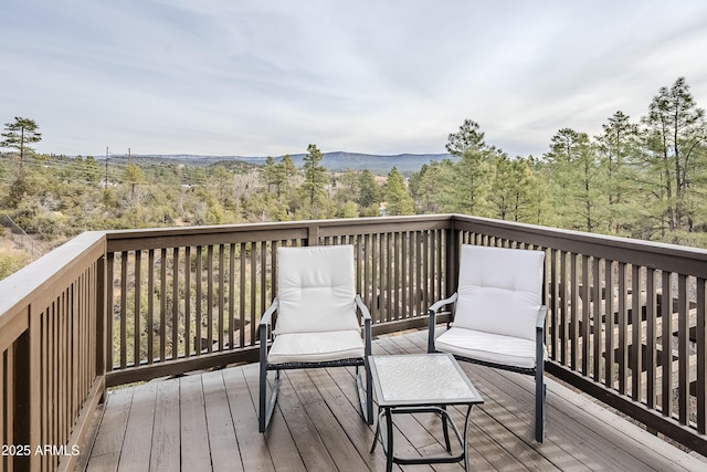 deck with a wooded view and a mountain view