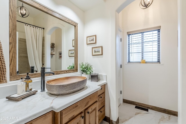 bathroom with marble finish floor, baseboards, and vanity