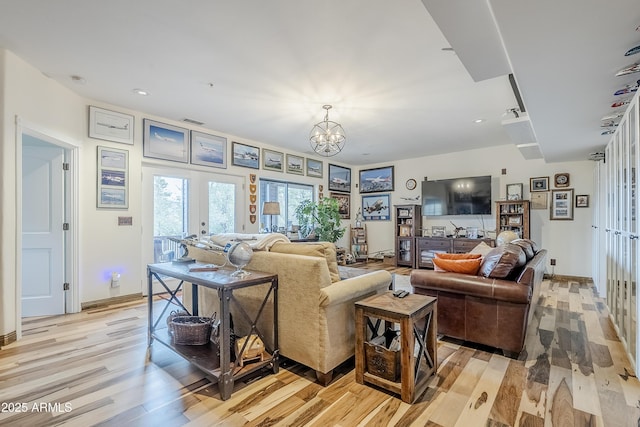 living room featuring light wood-style floors, visible vents, a notable chandelier, and french doors