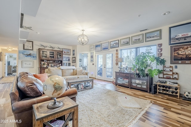 living room with a chandelier, french doors, wood finished floors, and visible vents