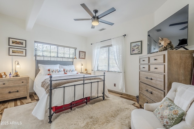 bedroom with a ceiling fan, visible vents, beam ceiling, and wood finished floors