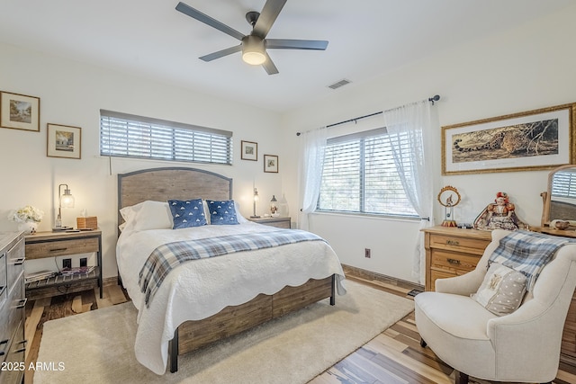 bedroom with baseboards, wood finished floors, visible vents, and a ceiling fan