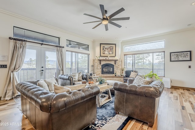 living area featuring light wood finished floors, crown molding, and a glass covered fireplace