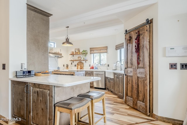 kitchen featuring a barn door, light wood-style flooring, a sink, dishwasher, and open shelves