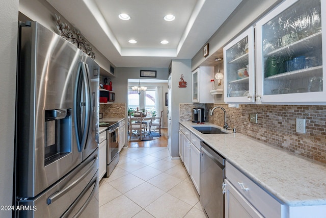 kitchen with white cabinets, sink, stainless steel appliances, an inviting chandelier, and light hardwood / wood-style floors