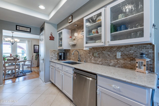 kitchen featuring pendant lighting, white cabinets, sink, stainless steel dishwasher, and an inviting chandelier