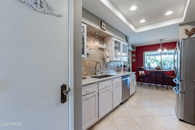 kitchen with stainless steel appliances, white cabinetry, a raised ceiling, and sink