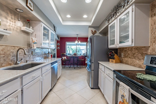 kitchen with tasteful backsplash, sink, white cabinets, hanging light fixtures, and appliances with stainless steel finishes