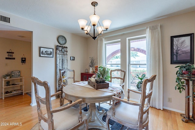 dining space with light hardwood / wood-style flooring and a chandelier