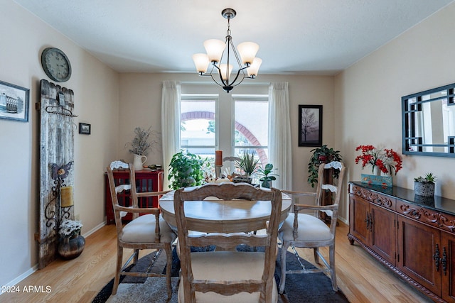 dining space with light hardwood / wood-style flooring and a notable chandelier