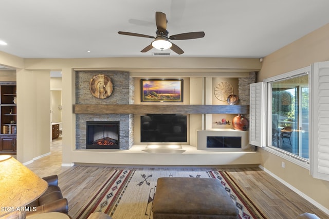 unfurnished living room featuring ceiling fan, a stone fireplace, and hardwood / wood-style floors