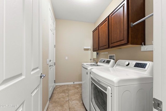 laundry area with light tile patterned floors, cabinets, and washer and clothes dryer