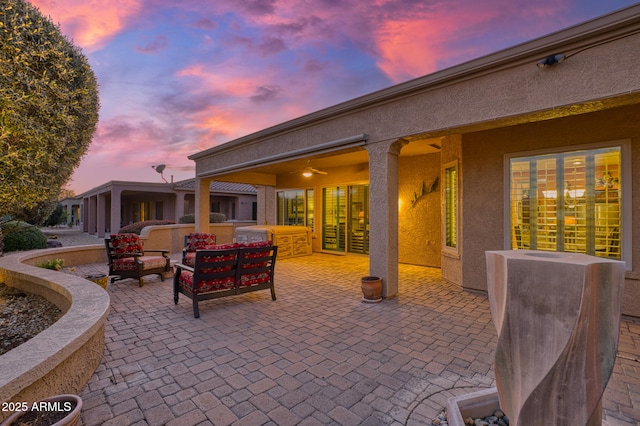 patio terrace at dusk featuring ceiling fan and an outdoor living space