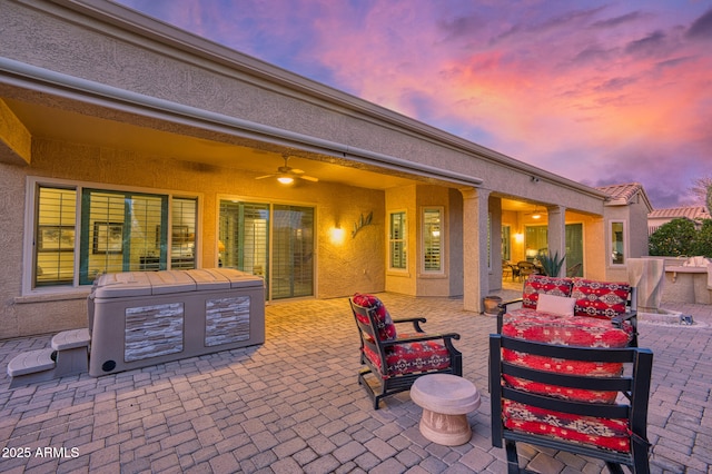 patio terrace at dusk featuring ceiling fan and an outdoor living space