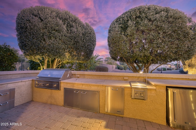 patio terrace at dusk with area for grilling and exterior kitchen