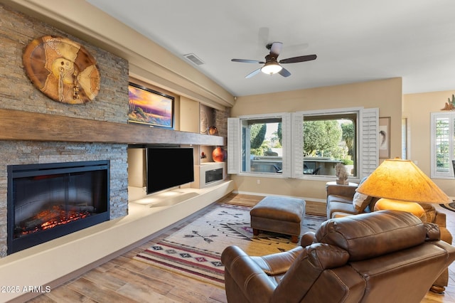 living room with hardwood / wood-style flooring, ceiling fan, and a fireplace