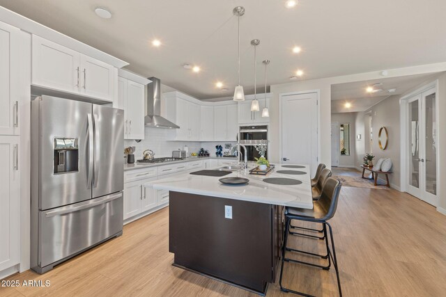 4947 N Mclaury Dr, Prescott Valley, AZ 86314 - kitchen with white cabinets, wall chimney exhaust hood, stainless steel appliances, tasteful backsplash, and an island with sink