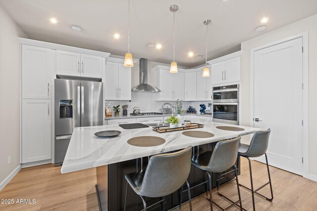 4947 N Mclaury Dr, Prescott Valley, AZ 86314 - kitchen with white cabinets, a breakfast bar area, appliances with stainless steel finishes, and wall chimney exhaust hood