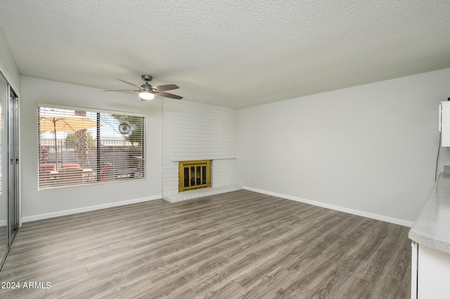 unfurnished living room with a textured ceiling, a fireplace, wood finished floors, and baseboards