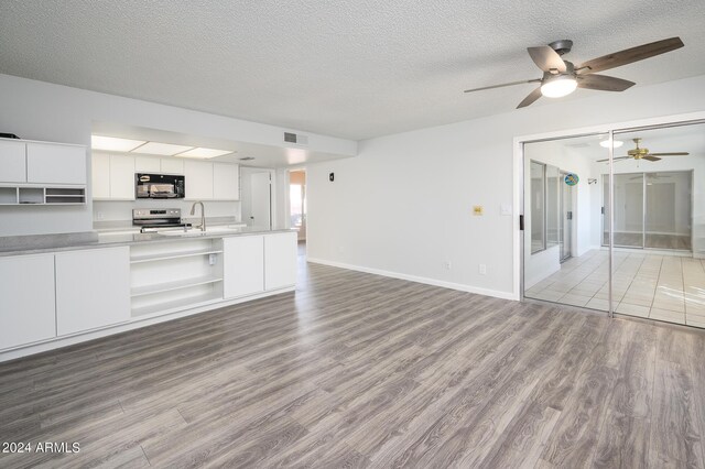 kitchen with electric stove, open shelves, open floor plan, wood finished floors, and black microwave