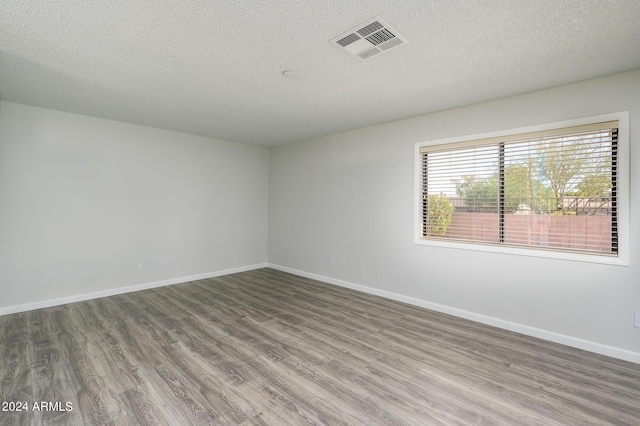 unfurnished room featuring baseboards, a textured ceiling, visible vents, and wood finished floors