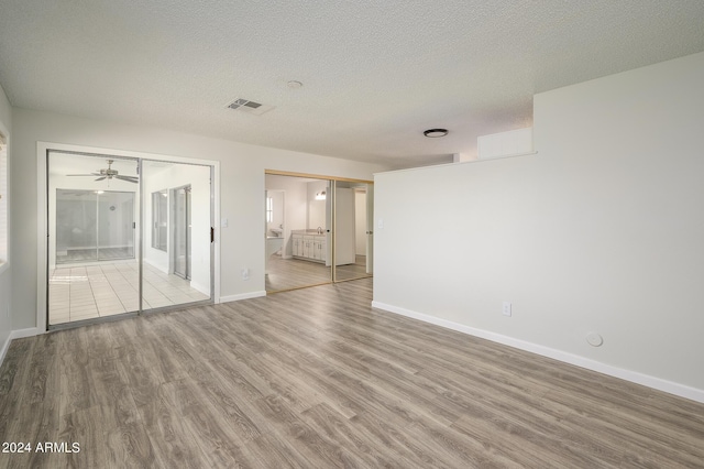 spare room with a textured ceiling, wood finished floors, visible vents, and baseboards