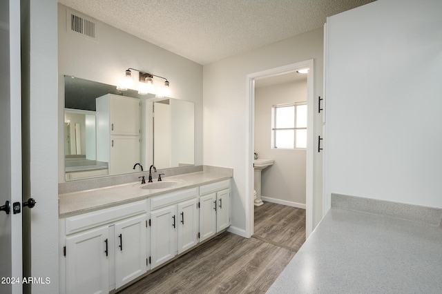 bathroom featuring visible vents, toilet, a textured ceiling, vanity, and wood finished floors