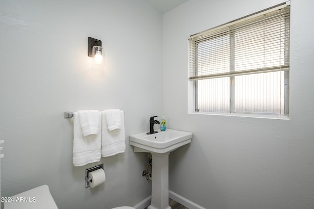 bathroom featuring toilet, baseboards, and a sink