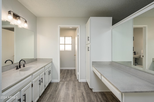 bathroom with a textured ceiling, wood-type flooring, and vanity