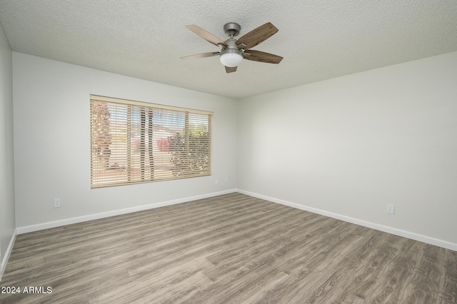 spare room with ceiling fan, a textured ceiling, baseboards, and wood finished floors