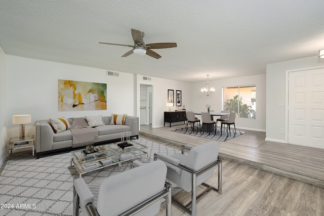 living room featuring a textured ceiling, ceiling fan with notable chandelier, and light hardwood / wood-style floors