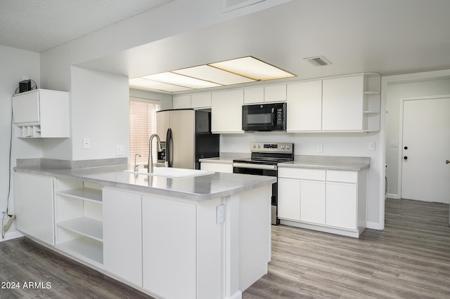 kitchen featuring appliances with stainless steel finishes, wood-type flooring, kitchen peninsula, and white cabinetry