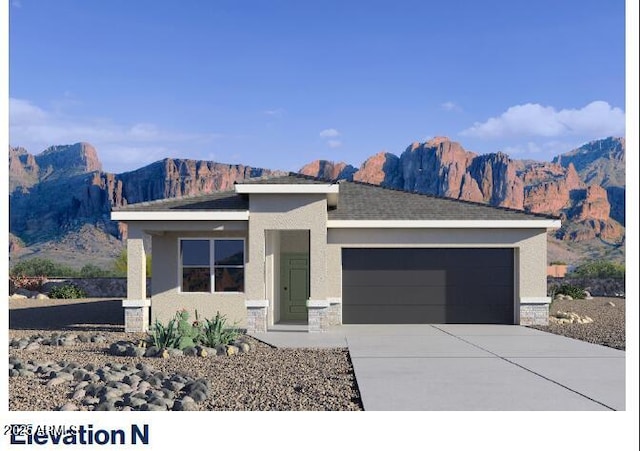 view of front of home with stucco siding, driveway, an attached garage, and a mountain view