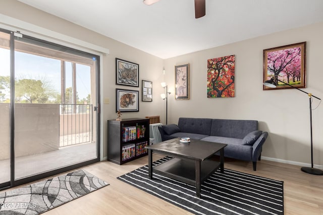 living room with a ceiling fan, baseboards, and wood finished floors