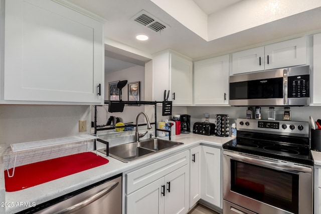 kitchen featuring appliances with stainless steel finishes, a sink, visible vents, and white cabinets