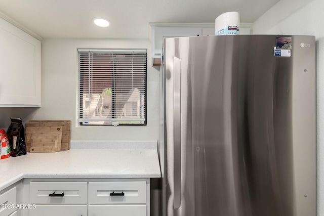 kitchen with white cabinetry, light stone counters, and freestanding refrigerator