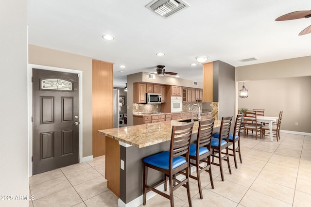 kitchen with ceiling fan, stainless steel microwave, visible vents, and oven
