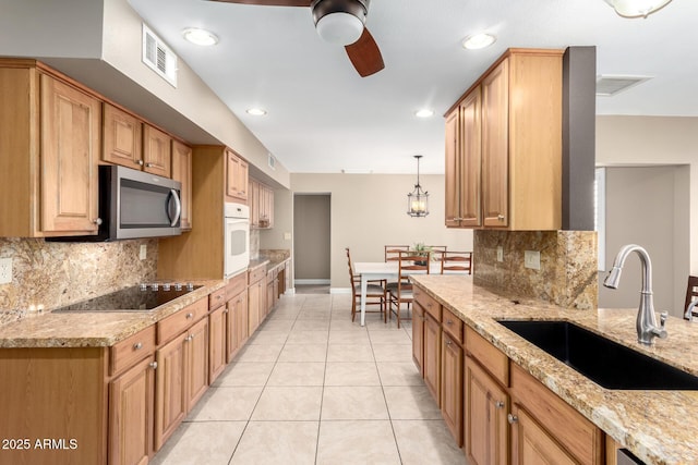kitchen with oven, a sink, black electric cooktop, stainless steel microwave, and visible vents