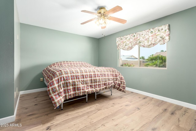 bedroom featuring a ceiling fan, baseboards, and wood finished floors