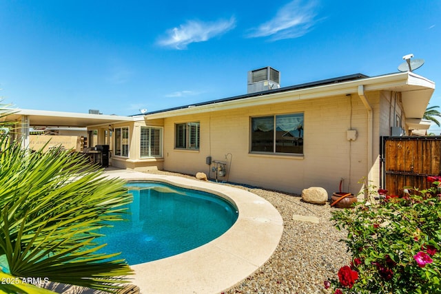 rear view of property featuring fence, a fenced in pool, and a patio