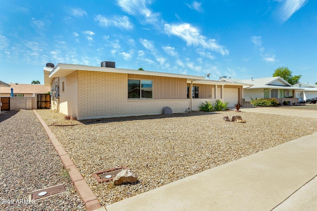single story home featuring fence, an attached garage, driveway, and brick siding