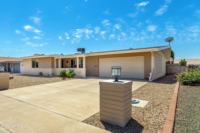 ranch-style home with brick siding, an attached garage, driveway, and fence